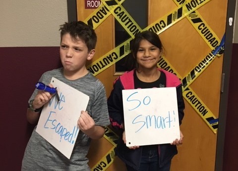 Students holding signs outside of the escape room